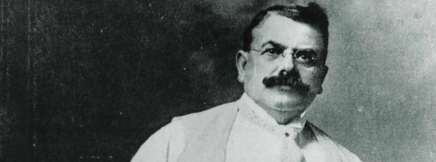 Black and white photo of Wallace C. Abbott.  He has short dark hair and a full, dark mustache and is wearing glasses and a white shirt, a suit vest and a tie.